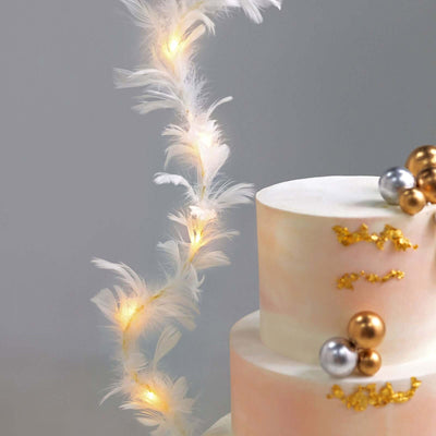 Elegant cake adorned with feathers and festive decorations.
