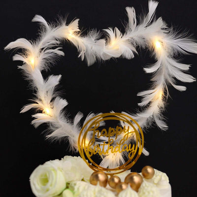 White feather heart decoration with lights and gold "Happy Birthday" sign.