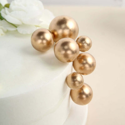Gold decorative beads arranged on a white cake.