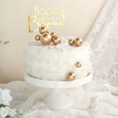 White birthday cake with gold decorations on a stand.