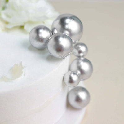 Silver pearl cake decorations on a white cake.