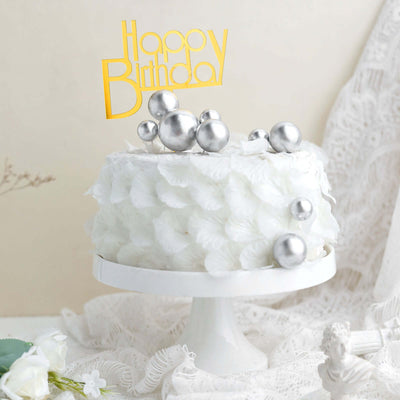 White birthday cake with silver decorations and a "Happy Birthday" topper.