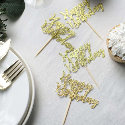 Gold glitter birthday cake toppers on a table setting.