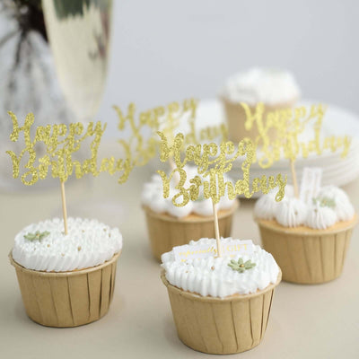 Birthday cupcakes with gold glitter toppers on a neutral background.