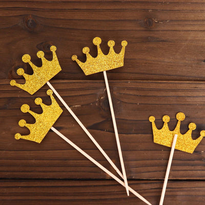 Gold crown cake toppers on wooden background.