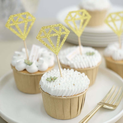 Gold diamond cupcake toppers on frosted cupcakes in decorative wrappers.