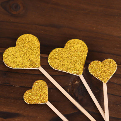 Gold glitter heart cake toppers on wooden sticks.