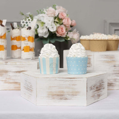 Cupcake decorations in blue and white with whipped cream on a rustic display.