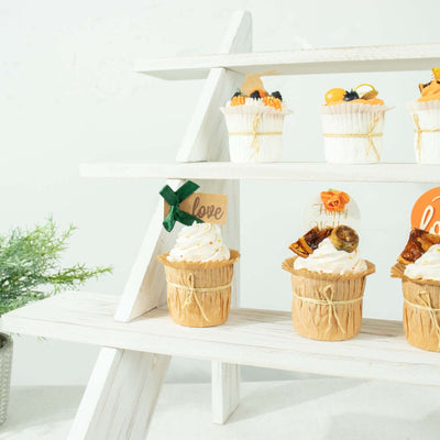 Decorative cupcakes on a wooden display stand with festive toppers and greenery.