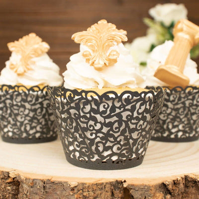 Elegant cupcake wrappers with intricate black lace design and ornate gold toppers.