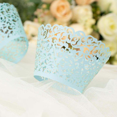 Blue decorative lace paper cupcake wrappers on a soft white background.