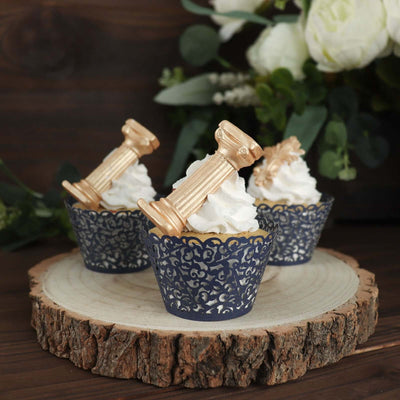 Elegant cupcakes with golden column toppers on rustic wood slice.