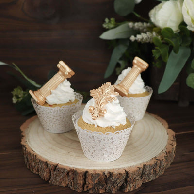 Decorative cupcakes with ornate toppers on a wooden slice base.