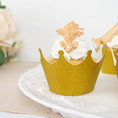 Gold crown cupcake wrapper with cream frosting and decorative topper.
