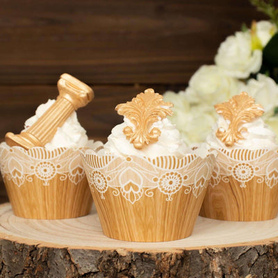 Decorative cupcakes with ornate gold toppers on a rustic wooden surface.