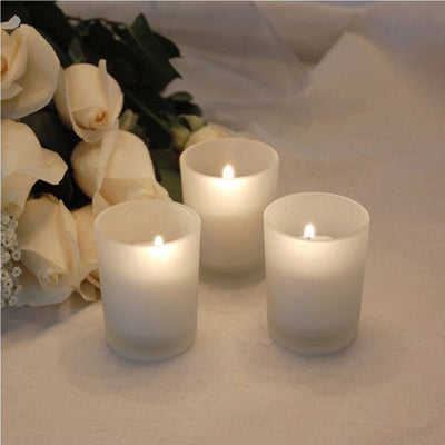 Frosted glass candle trio with soft glowing flames against a light backdrop.