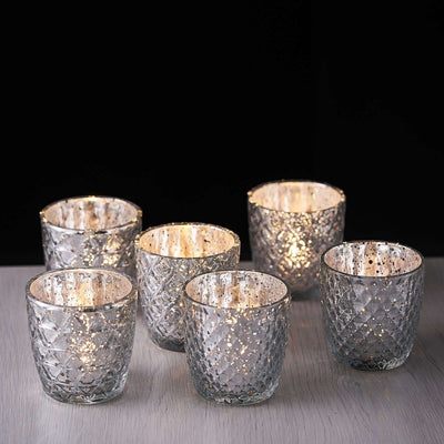 Set of six decorative glass votive candle holders with intricate patterns.