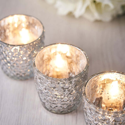 Set of three textured glass candle holders with glowing candles.