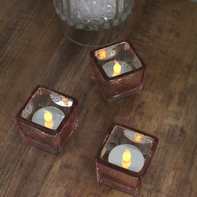 Decorative LED candle holders with flickering flames on a wooden surface.