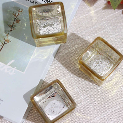 Set of three gold-accented glass candle holders on a table.