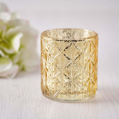 Gold geometric glass candle holder on a soft textured surface.