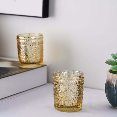 Decorative amber glass candle holders on a shelf with a plant.