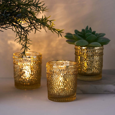 Decorative gold candle holders with lit candles and a succulent plant.