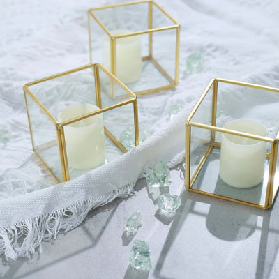 Gold and glass candle holders with white candles and decorative glass pieces.