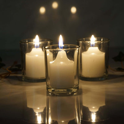 Three white candles in glass holders with soft reflections.