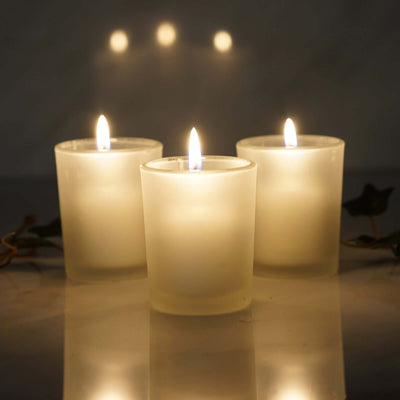 Frosted glass candles with warm flames glowing in a serene setting.