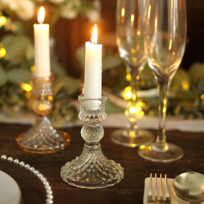 Elegant crystal candle holders with lit candles and champagne flutes on a table.