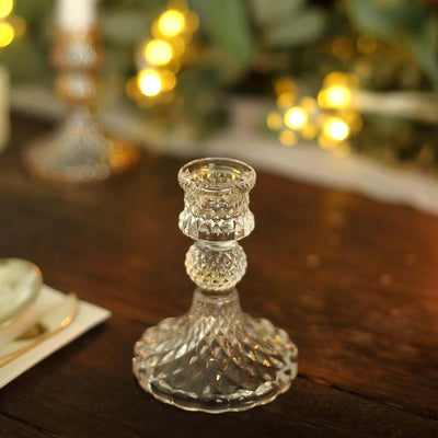 Crystal candlestick holder on a wooden table with soft glowing lights in the background.