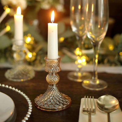 Elegant crystal candle holder with a lit candle, set on a beautifully arranged table.