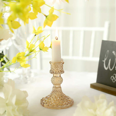Elegant glass candle holder with a lit candle, surrounded by flowers and decor.