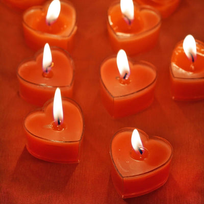 Heart-shaped orange candles with flames glowing brightly.