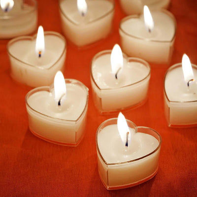 Heart-shaped candles glowing softly on an orange surface.