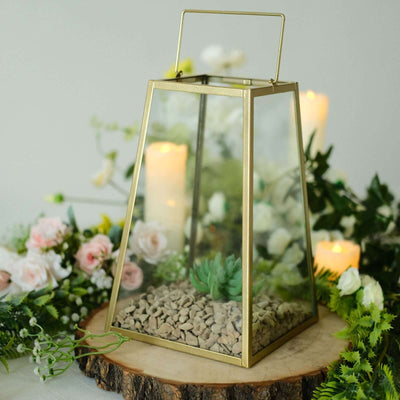 Geometric glass lantern with succulent and pebbles, surrounded by flowers and candles.