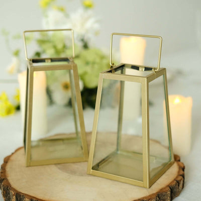 Gold lanterns on a wooden slice with candles and flowers in the background.