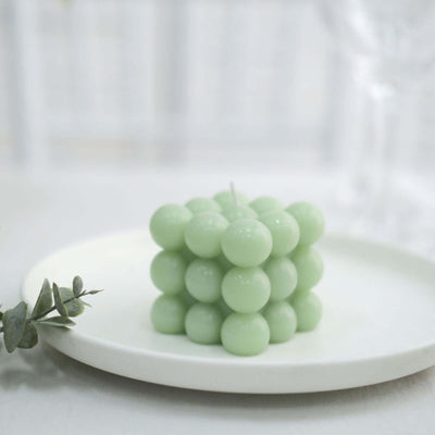 Green bubble candle on a white plate with greenery