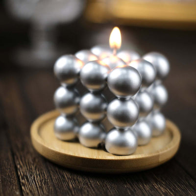 Silver decorative candle on a wooden plate with a soft glow.