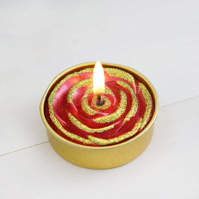 Red rose-shaped candle with gold glitter and flame