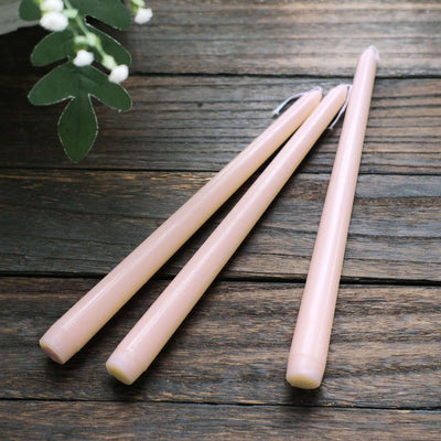 Pink taper candles on a wooden surface.