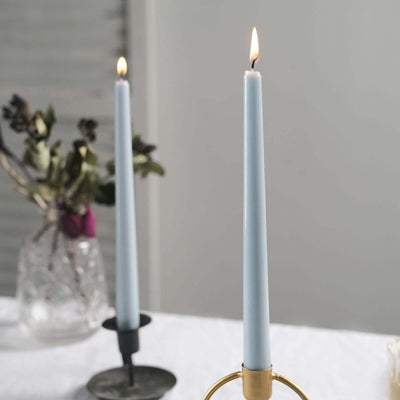 Blue taper candles in elegant holders on a dining table.