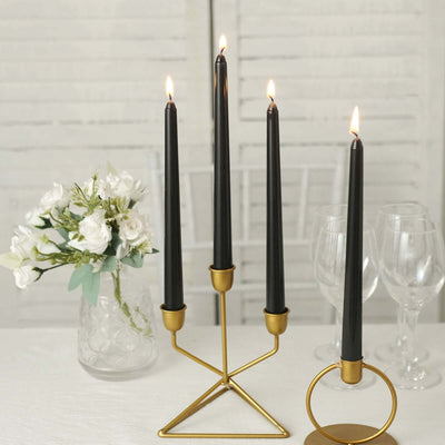 Elegant black candle holder with four tall candles and a floral arrangement.