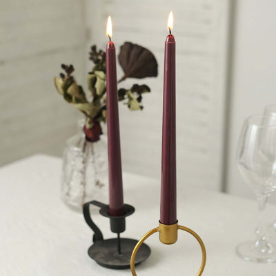 Elegant burgundy candles in a modern candle holder with dried flowers.