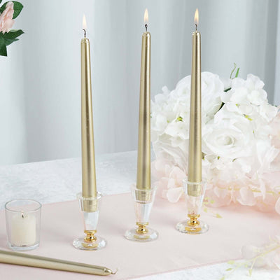 Three elegant gold taper candles in crystal holders with white flowers backdrop.