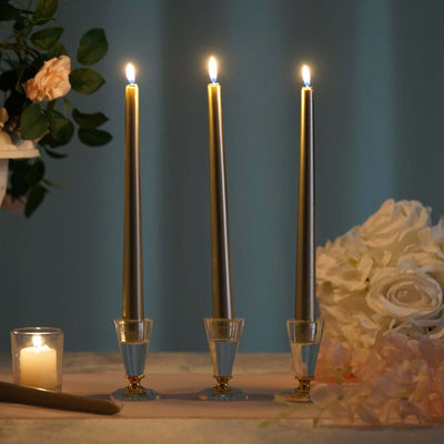 Elegant set of three tall golden candles with glass holders glowing softly.
