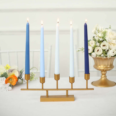 Elegant candle holder with five colorful candles and floral arrangement in the background.