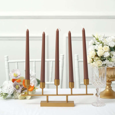 Elegant candle holder with five brown candles and decorative flowers.