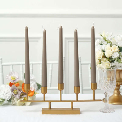 Elegant gold candle holder with four gray candles and floral decor.